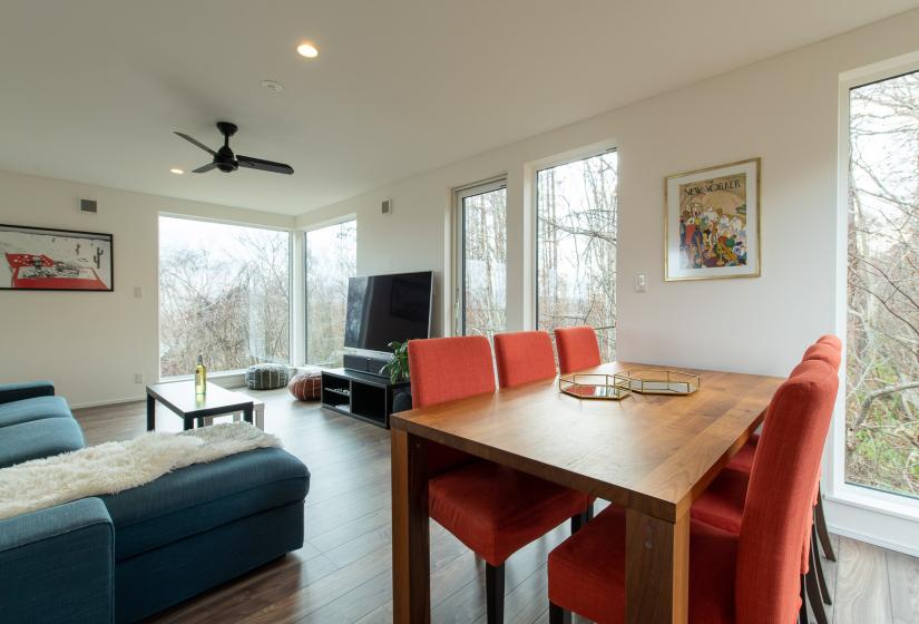 A wooden dining table with red chairs and television behind.