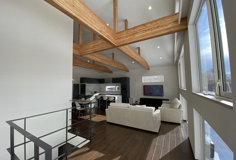The view of a living room with TV at the far end and exposed beams above