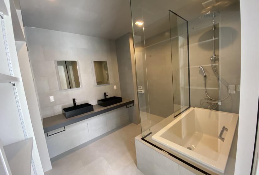 A tiled bath room with 2 basins and large bath