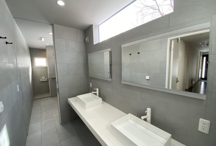 Two sinks in a grey tiled bathroom