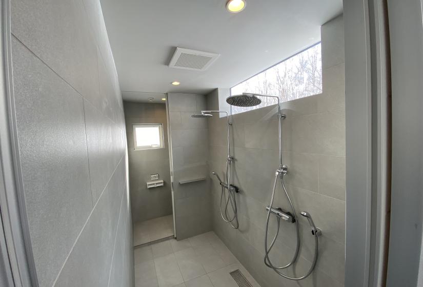 A grey tiled bathroom with two rain showers