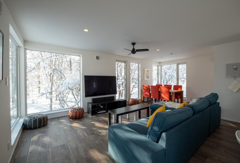 A blue couch with TV and large windows behind.