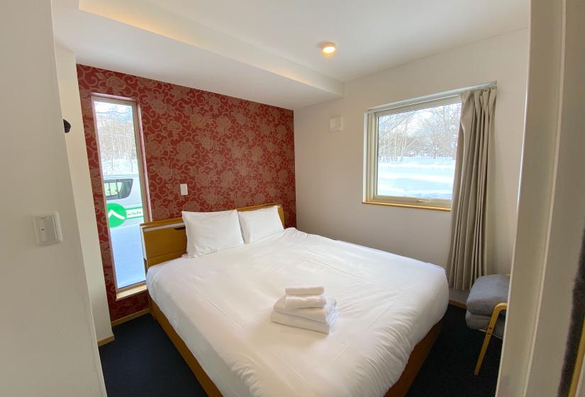 A bedroom with double bed and red wall behind