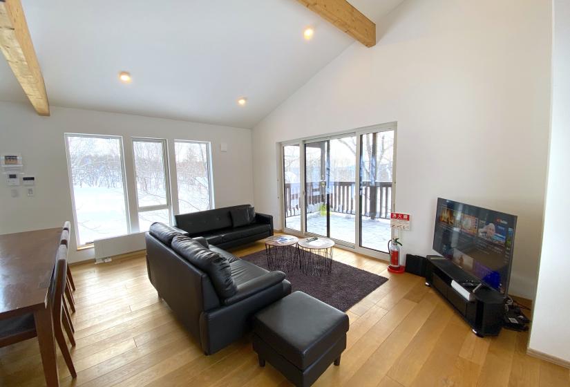 A living room with black couch and television in right corner