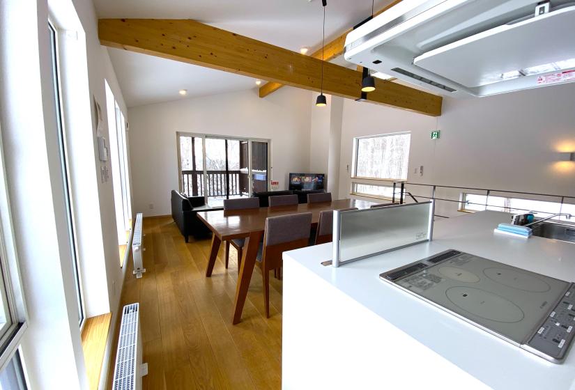 A kitchen bench and stove top with living area behind