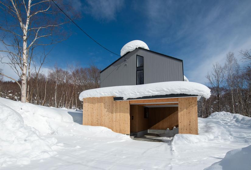 Blue skies behind a two story home capped with snow