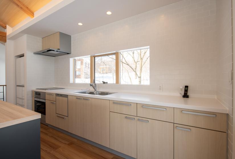 A long white kitchen bench with windows behind  