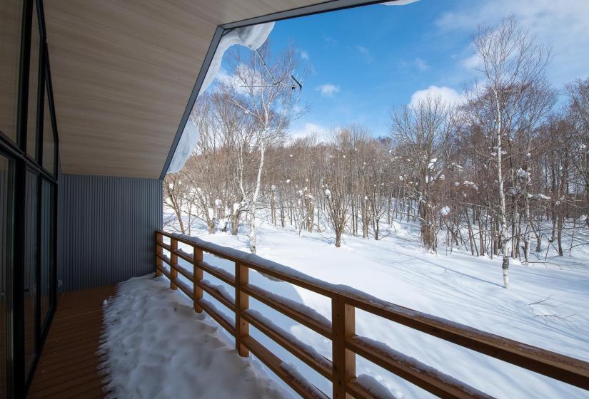 Balcony view of trees and snowy surrounds.