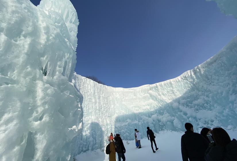 Groups of people enjoying a large ice cavern under blue skies