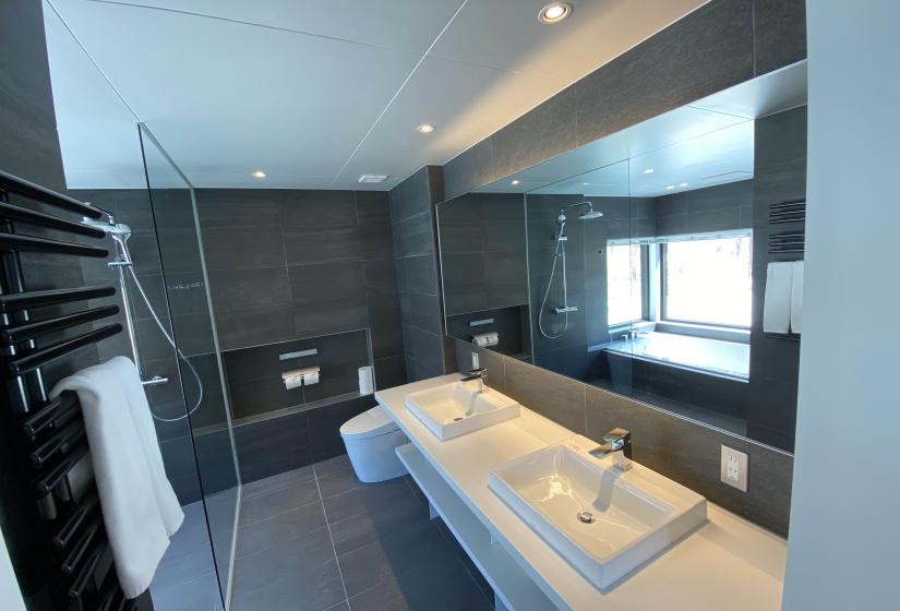 A black tiled bathroom with bath in mirror reflection