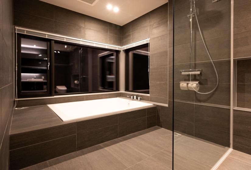 A white spa bath in a black tiled bathroom