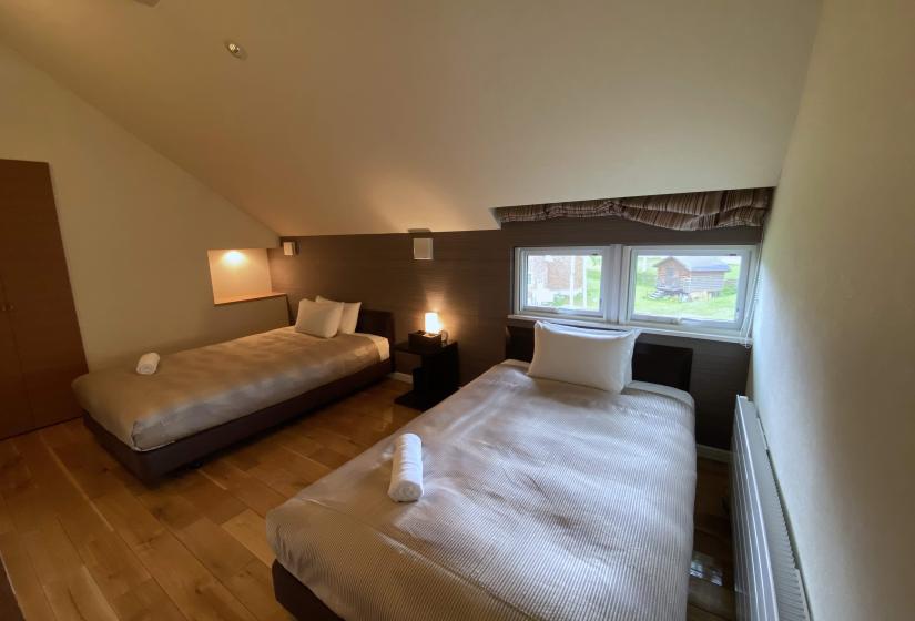 Two made up single beds in a rom with a pitched ceiling