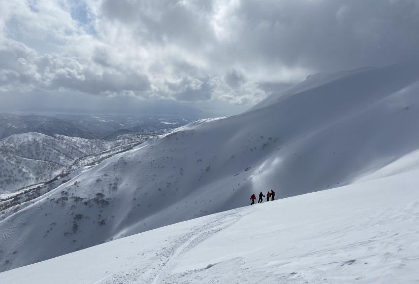 A group of skiers stand on amongst a rolling mountain range.