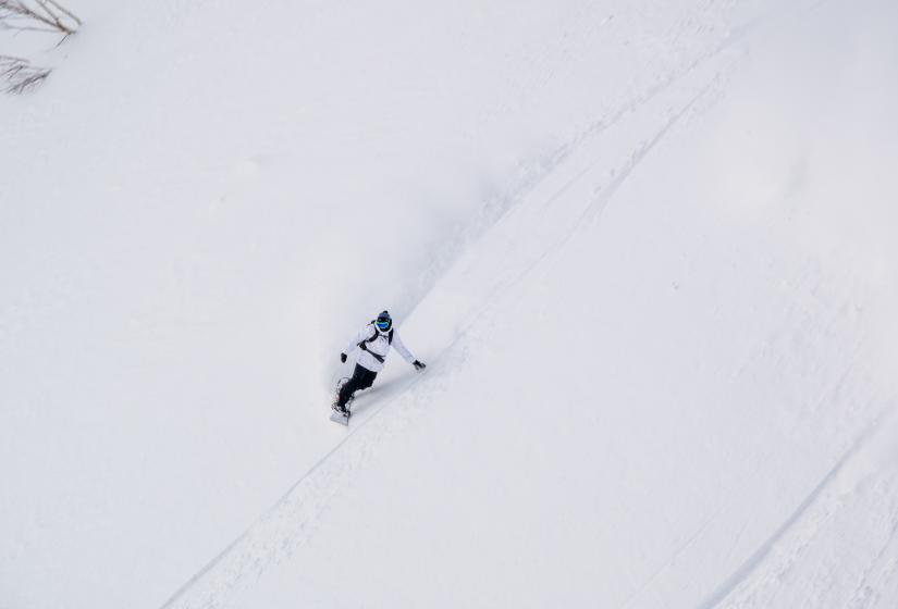 A snowboarder makes a turn in powder snow