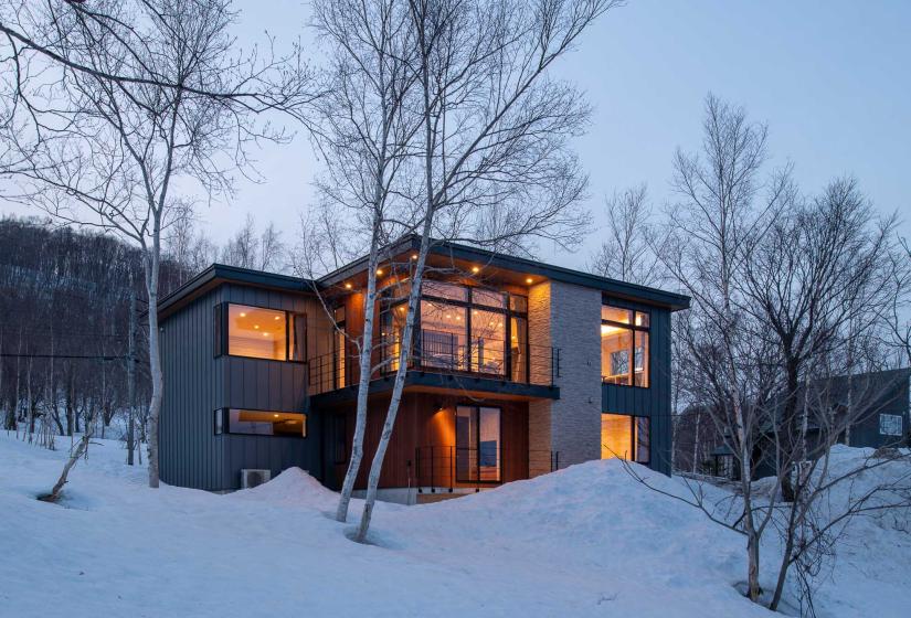 A 2 story home at dusk with lights on.