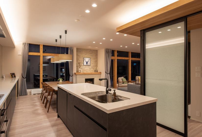 A kitchen island and dining table behind