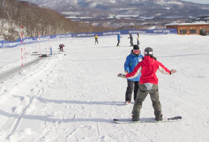 A snowboarder takes a private lesson