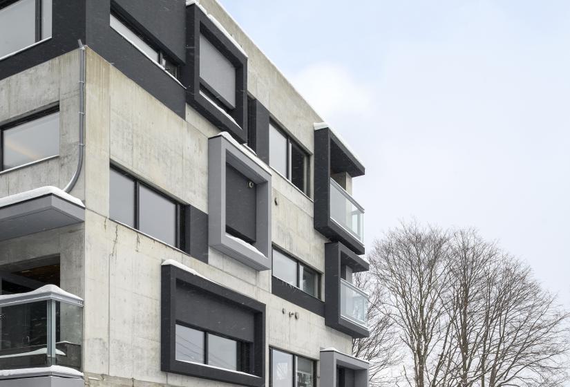 a 4 story concrete building with black windows.