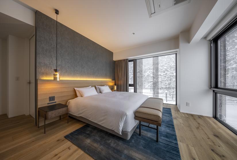 A made up hotel room with white bed spread.