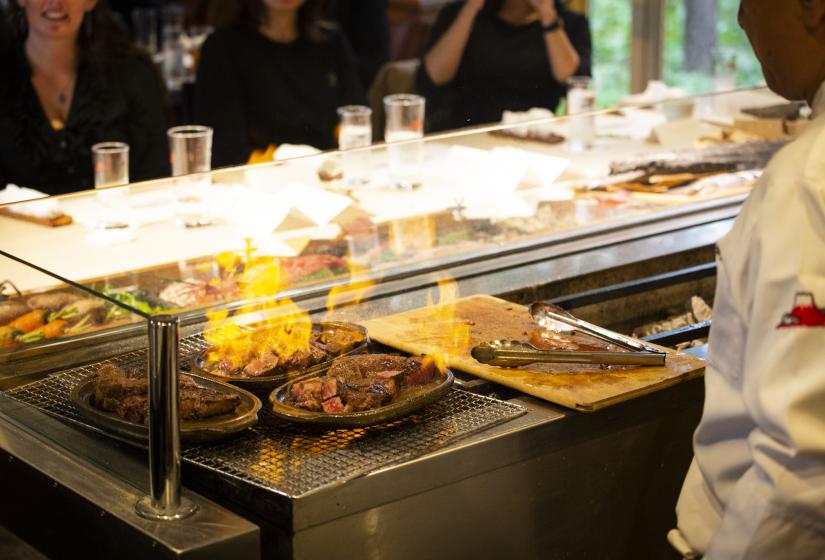 Guests can relax and dine in Intuitions own restaurant and bar. A chef works behind a grill with flames