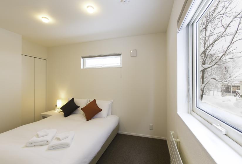 A white double bed with window to the left