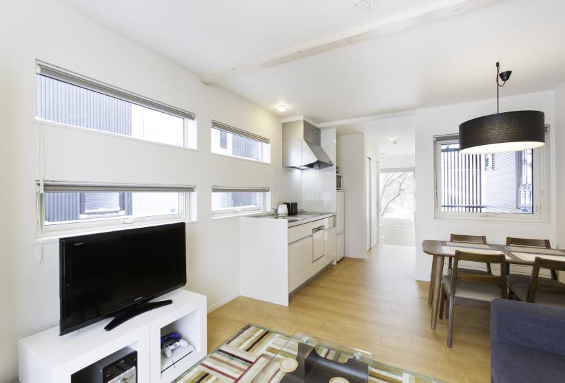 A television to the left and kitchen and dining table behind