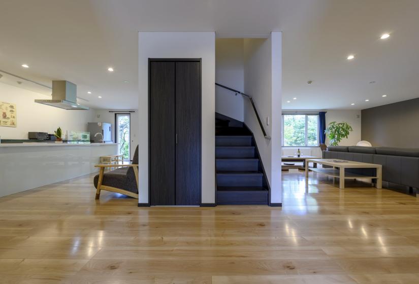 A lounge and kitchen divided by a staircase