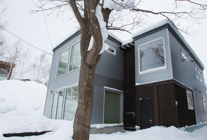 A two story building in the snow with tree in foreground