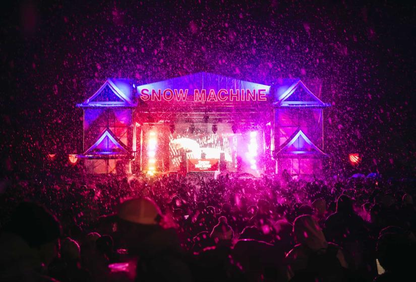 A large crowd in front of a neon lit stage