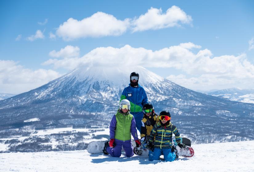 Snowboarder with their instructor and Mount Yotei in the back ground