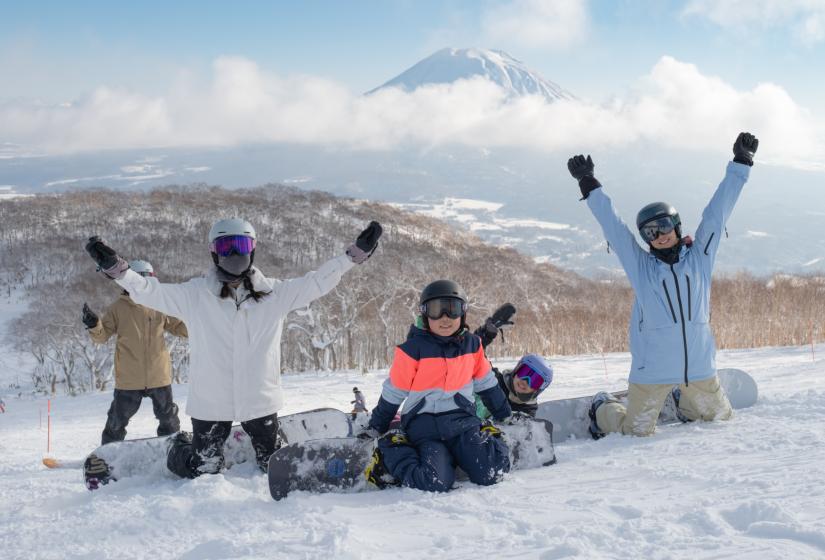 4 snowboarders kneeling in the snow