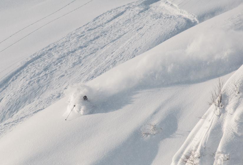 All guided tours include access to secret stashes! A skier makes a deep turn in the powder