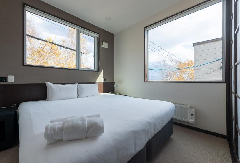 A made up double bed and window beside