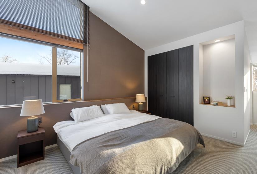 A made up double bed with grey throw