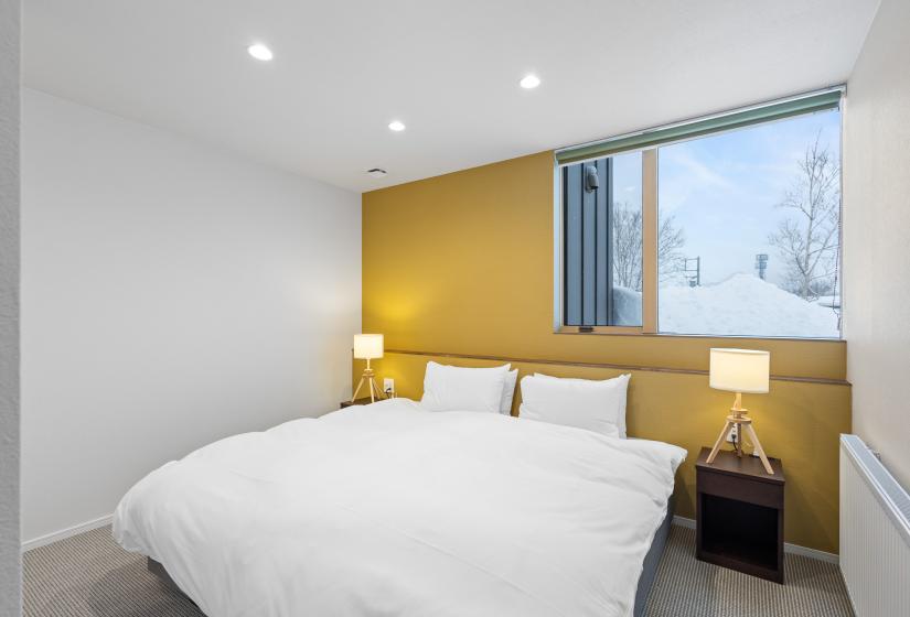 A made up double bed with green wall behind