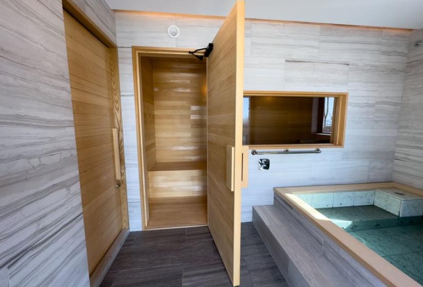 Niseko Chalet Taiko's wellness area featuring private jacuzzi and sauna entrance with stone tile walls