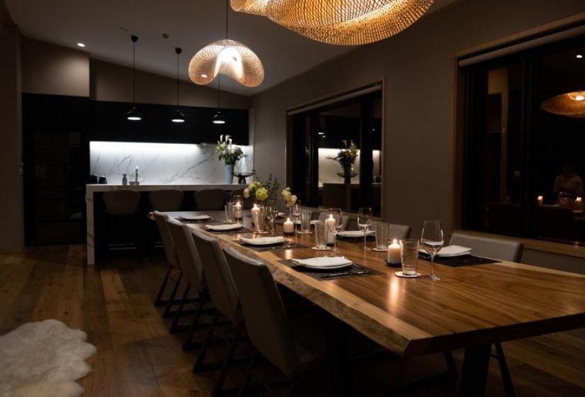 Niseko Chalet Taiko's dining area at night with atmospheric lighting, featuring wooden table and designer pendant lamps