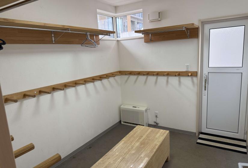 Dedicated ski drying room at Yutaka Townhouses with wooden wall hooks, bench seating, and ample storage space for ski gear and equipment, offering practical amenities for guests during their Niseko ski vacation.