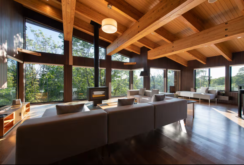 Luxury Niseko chalet with wooden beam ceiling, floor-to-ceiling windows and panoramic forest views