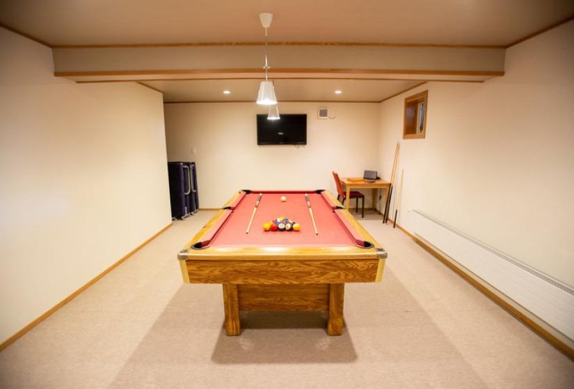 Basement games room with wooden pool table featuring red felt, white walls, wooden trim, and ceiling-mounted lighting at Chalet Creekside.