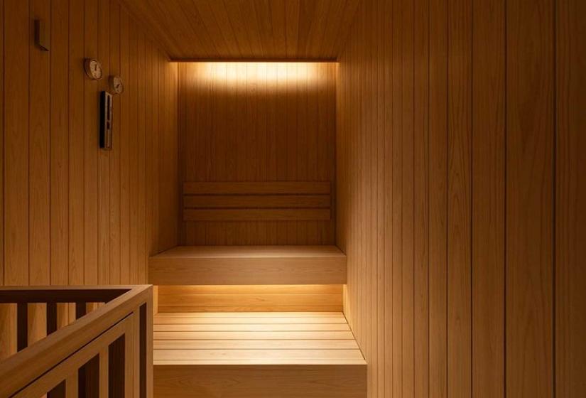Luxurious Finnish sauna with warm cedar wood paneling, built-in bench seating, and soft ambient lighting - an essential après-ski relaxation amenity in this premium Niseko vacation property.