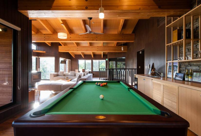 Luxury Niseko chalet game room with pool table, wooden beam ceiling and panoramic forest views