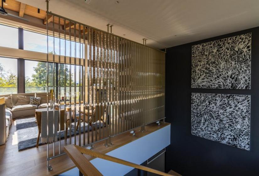 Interior of Chalet Lotus Niseko showcasing elegant Japanese-inspired design with wooden slatted room divider, distinctive black wall art, contemporary furniture, and large windows allowing natural light to highlight the sophisticated alpine retreat aesthetics.