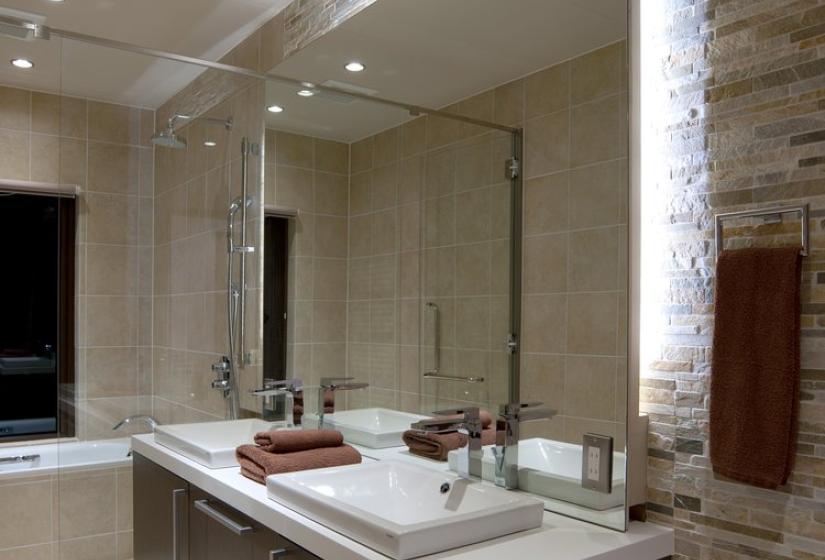 Elegant bathroom in Chalet Snowbird with stone accent wall, floating double vanity with white countertop, large mirror, recessed lighting, and contemporary fixtures.