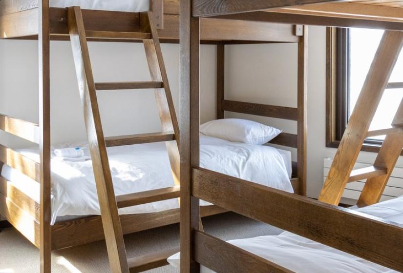 Custom wooden bunk beds with ladder access in Chalet Snowbird Niseko, featuring premium linens and thoughtful Japanese-inspired design elements.