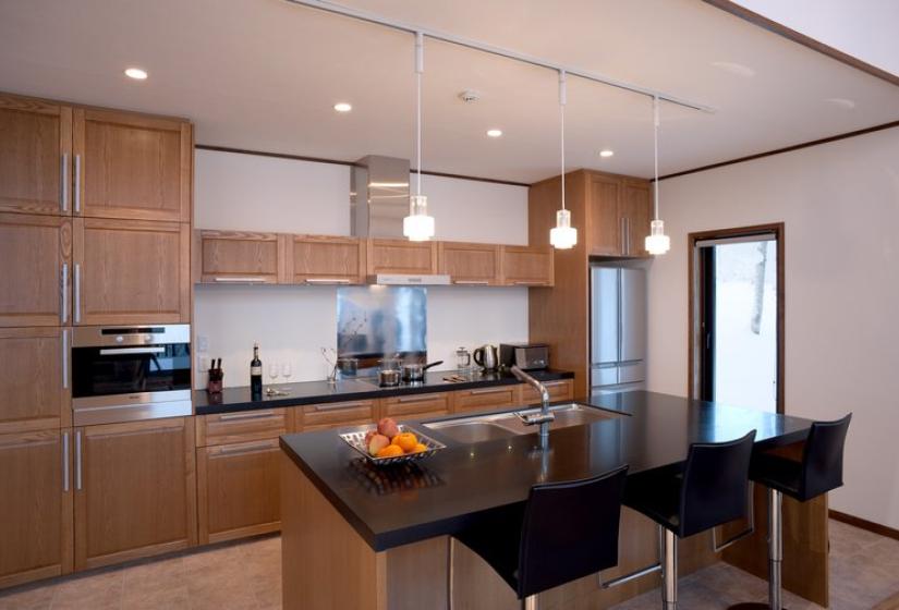 Modern kitchen with wooden cabinetry, central island with bar seating, stainless steel appliances, and recessed lighting in Chalet Snowbird.