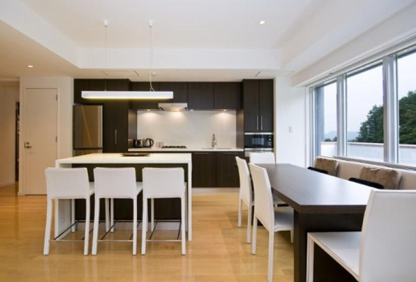 Alpen Ridge Niseko 3 bedroom apartment featuring minimalist open kitchen with breakfast bar white dining furniture wooden flooring large windows natural lighting and contemporary design