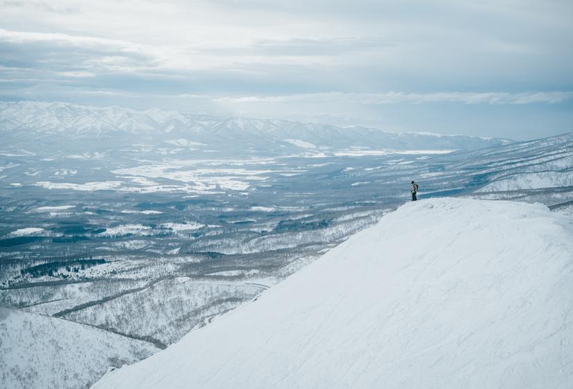 The Niseko area is larger than you may think with wide range of locations to choose from. A man standing on a snowy ridge