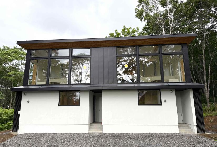 A black and white townhouse with large windows.