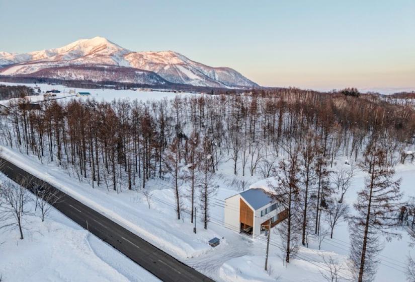 An arial photo of a white house with Mt Yotei behind